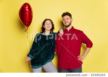 Happy couple, man and woman holding balloons shaped hearts and gift box. Valentine's day celebration. Concept of emotions, love, relations, romantic holidays. Happy couple, man and woman holding balloons shaped hearts and gift box. Valentine's day celebration. Concept of emotions, love, relations, romantic holidays. 85990264