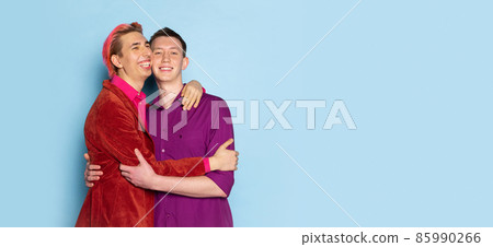 Portrait of young men, couple posing isolated on blue background. Concept of emotions, love, relations, romantic, diversity Portrait of young men, couple posing isolated on blue background. Concept of emotions, love, relations, romantic, diversity 85990266