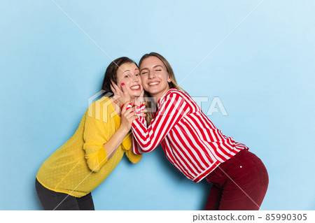 Studio shot of emotional young girls, couple isolated on blue background. Valentine's day celebration. Concept of emotions, love, relations, romantic holidays. Studio shot of emotional young girls, couple isolated on blue background. Valentine's day celebration. Concept of emotions, love, relations, romantic holidays. 85990305
