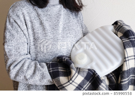 A woman holding a hot water bottle 85990558