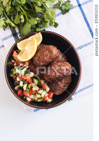 Fried minced meat kofta or kebabs served with vegetable saladf in a bowl. Close up. Middle eastern food concept. 85991010