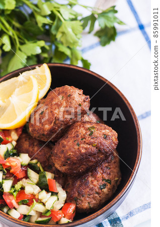 Fried minced meat kofta or kebabs served with vegetable saladf in a bowl. Close up. Middle eastern food concept. Fried minced meat kofta or kebabs served with vegetable saladf in a bowl. Close up. Middle eastern food concept. 85991011
