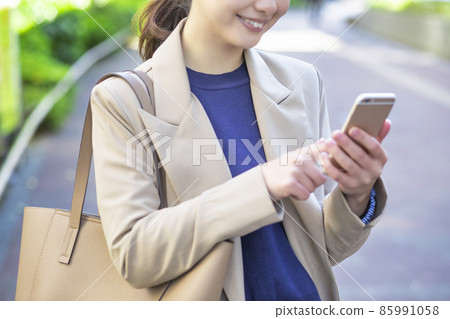 A woman who stops and checks information on her smartphone A woman who stops and checks information on her smartphone 85991058