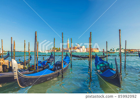 Watercolor drawing of Gondolas moored docked on water in Venice. Gondoliers sailing San Marco basin waterway. San Giorgio Maggiore island 85992092