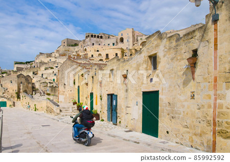 Watercolor drawing of Motorcyclists in helmets riding a motorcycle on stone streets in Matera historical centre Sasso Caveoso Watercolor drawing of Motorcyclists in helmets riding a motorcycle on stone streets in Matera historical centre Sasso Caveoso 85992592