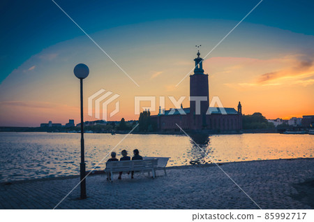 Watercolor drawing of Silhouette of women sitting on bench at promenade of Lake Malaren looking at Stockholm City Hall Stadshuset tower Watercolor drawing of Silhouette of women sitting on bench at promenade of Lake Malaren looking at Stockholm City Hall Stadshuset tower 85992717