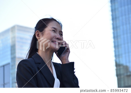 一位微笑的高級女商人在辦公區用手機交談 一位微笑的高級女商人在辦公區用手機交談 85993472