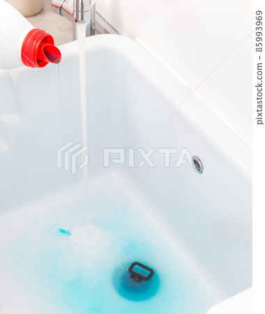 Pouring blue detergent into empty sink before washing clothes in laundry room 85993969