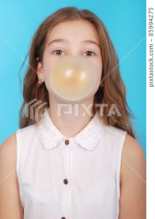 Young girl making a big bubble with a chewing gum Young girl making a big bubble with a chewing gum 85994275