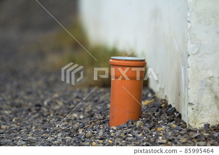 Drainage pipe in the recess of the gutter. Pipe for the water sticking from the ground. 85995464