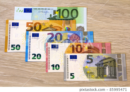 Different euro money banknotes on wooden background Different euro money banknotes on wooden background 85995471