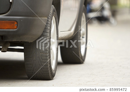 Detail of car, wheels with aluminum discs and new black rubber tire protector on light blurred background. Transportation, safety, reliability, modern design concept. Detail of car, wheels with aluminum discs and new black rubber tire protector on light blurred background. Transportation, safety, reliability, modern design concept. 85995472