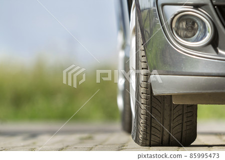 Detail of car, wheels with aluminum discs and new black rubber tire protector on light blurred background. Transportation, safety, reliability, modern design concept. Detail of car, wheels with aluminum discs and new black rubber tire protector on light blurred background. Transportation, safety, reliability, modern design concept. 85995473