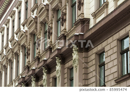 Detail image of facade of an old building. Windows and decoration of walls made in old style. Unique architecture Detail image of facade of an old building. Windows and decoration of walls made in old style. Unique architecture 85995474
