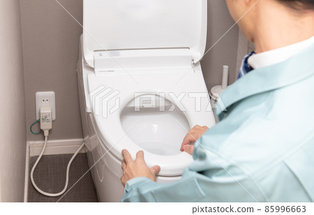 一個穿著工作服的男人正在檢查廁所 85996663