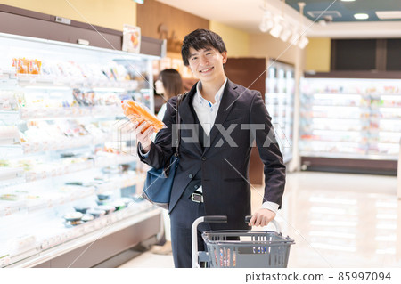 A businessman buying vegetables at a supermarket 85997094
