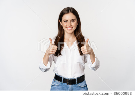 Happy smiling girl showing thumbs up, student with satisfied feedback, recommending smth, standing over white background Happy smiling girl showing thumbs up, student with satisfied feedback, recommending smth, standing over white background 86000998