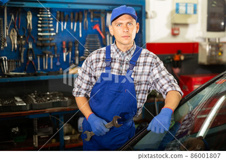 Workman standing near car at auto repair Workman standing near car at auto repair 86001807