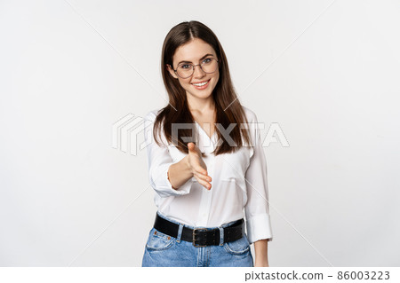 Corporate woman in office extending hand and smiling, handshake, greeting business partner, standing in glasses over white background 86003223