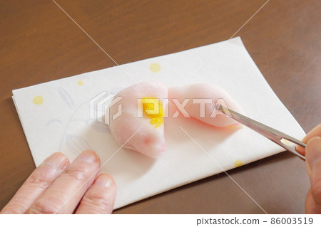 Divide Japanese sweets into two equal parts with a toothpick and stab them. 86003519