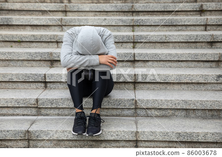 Upset woman sitting alone in city stairs 86003678