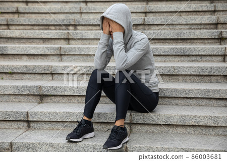 Upset woman sitting alone in city stairs 86003681