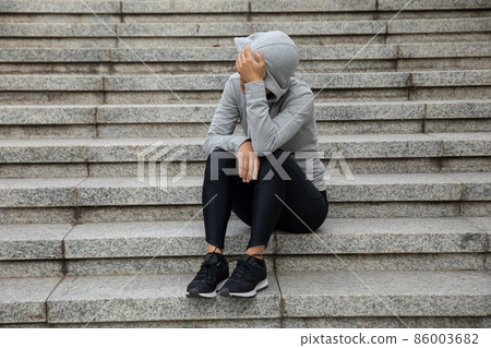 Upset woman sitting alone in city stairs Upset woman sitting alone in city stairs 86003682