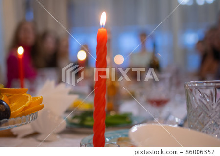 Elegant table set with glasses decorated in gold, lighted candles. Elegant table set with glasses decorated in gold, lighted candles. 86006352