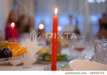 Elegant table set with glasses decorated in gold, lighted candles. 86006354