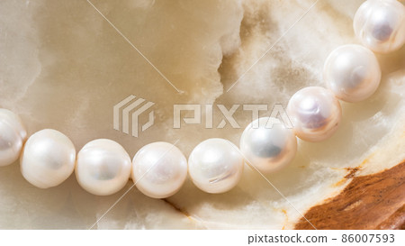 Nature white string of pearls on marble background in soft focus, with highlights 86007593