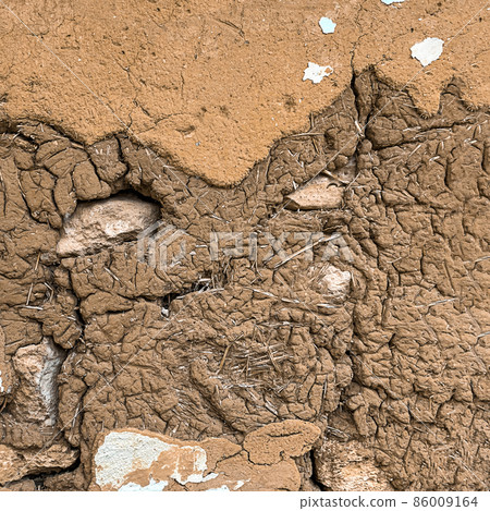 Adobe wall with stone and straw. Brown textured background. Adobe wall with stone and straw. Brown textured background. 86009164