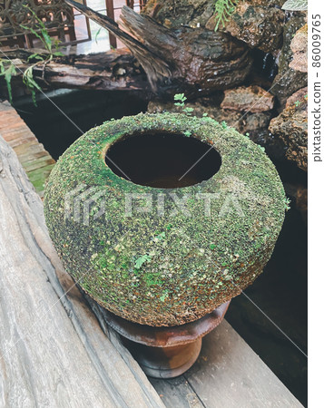 Big earthen jar made from clay covered with moss 86009765
