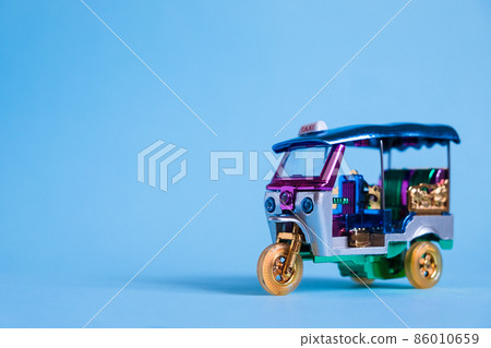 Model Toy tuk tuk isolated on blue background. Thai traditional taxi in Bangkok Thailand. Souvenir Model Toy tuk tuk isolated on blue background. Thai traditional taxi in Bangkok Thailand. Souvenir 86010659