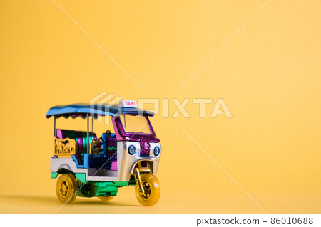 Model Toy tuk tuk isolated on yellow background. Thai traditional taxi in Bangkok Thailand. Souvenir Model Toy tuk tuk isolated on yellow background. Thai traditional taxi in Bangkok Thailand. Souvenir 86010688