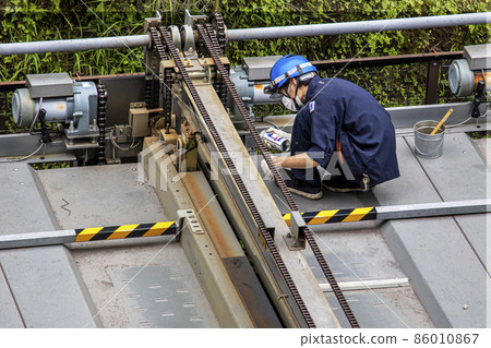 Male worker performing regular inspection and maintenance work on the pallet of the mechanical parking lot Male worker performing regular inspection and maintenance work on the pallet of the mechanical parking lot 86010867