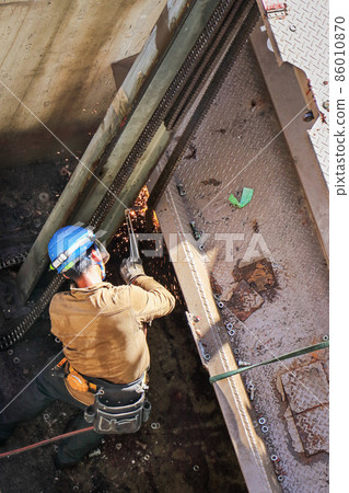Male worker performing cutting and welding work with a gas burner at a demolition construction site 86010870