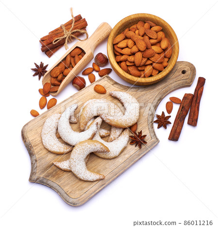 German or Austrian Vanillekipferl vanilla kipferl cookies and almond nuts on wooden serving board 86011216