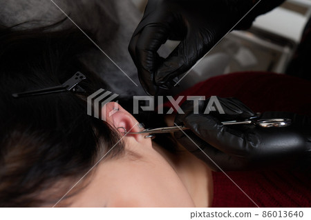 Professional holding the jewel of piercing day just before screw the ball. Tragus type. Professional holding the jewel of piercing day just before screw the ball. Tragus type. 86013640