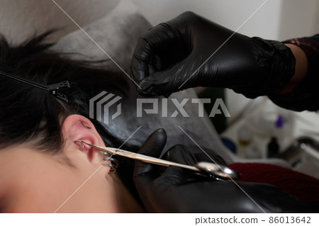 Professional holding the jewel of piercing day just before screw the ball. Tragus type. Professional holding the jewel of piercing day just before screw the ball. Tragus type. 86013642