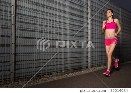 Running woman. jogging against the background of a gray wall 86014084