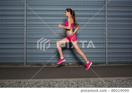 Running woman. jogging against the background of a gray wall Running woman. jogging against the background of a gray wall 86014099