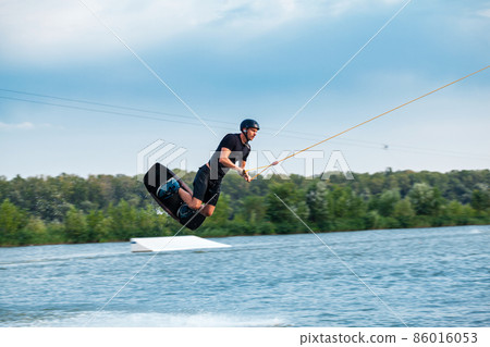Man practicing technique of jumping over water during wakeboarding training Man practicing technique of jumping over water during wakeboarding training 86016053