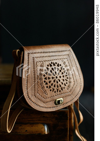 small brown women's leather bag with a carved pattern. selective focus small brown women's leather bag with a carved pattern. selective focus 86019948