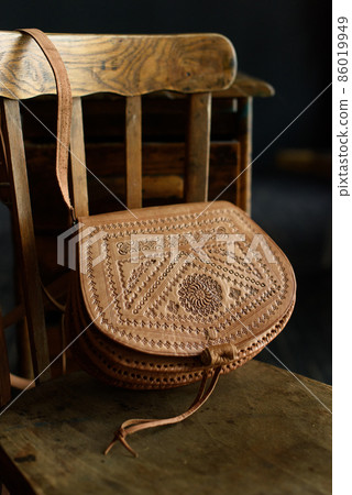 small brown women's leather bag with a carved pattern. selective focus small brown women's leather bag with a carved pattern. selective focus 86019949