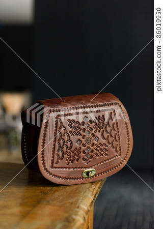 small brown women's leather bag with a carved pattern. selective focus 86019950