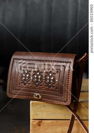 small brown women's leather bag with a carved pattern. selective focus small brown women's leather bag with a carved pattern. selective focus 86019960