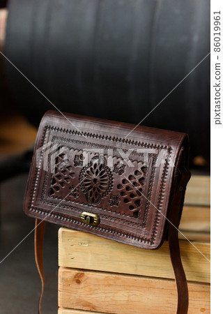 small brown women's leather bag with a carved pattern. selective focus small brown women's leather bag with a carved pattern. selective focus 86019961