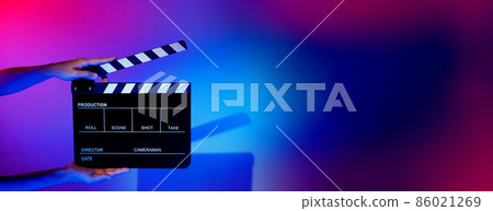 Blurry images of movie slate or clapper board. Hand holds empty film making clapperboard on color background in studio for film movie shooting or recording. Film slate for Youtuber video production. 86021269