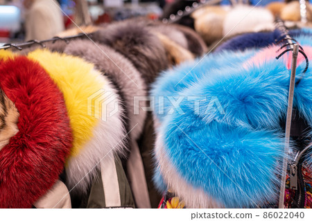 Fur coats in a row on a hanger in the store. Female fashion, natural mink fur clothes of different colors 86022040