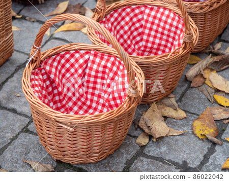 Wicker basket with red napkin on the floor, closeup Wicker basket with red napkin on the floor, closeup 86022042